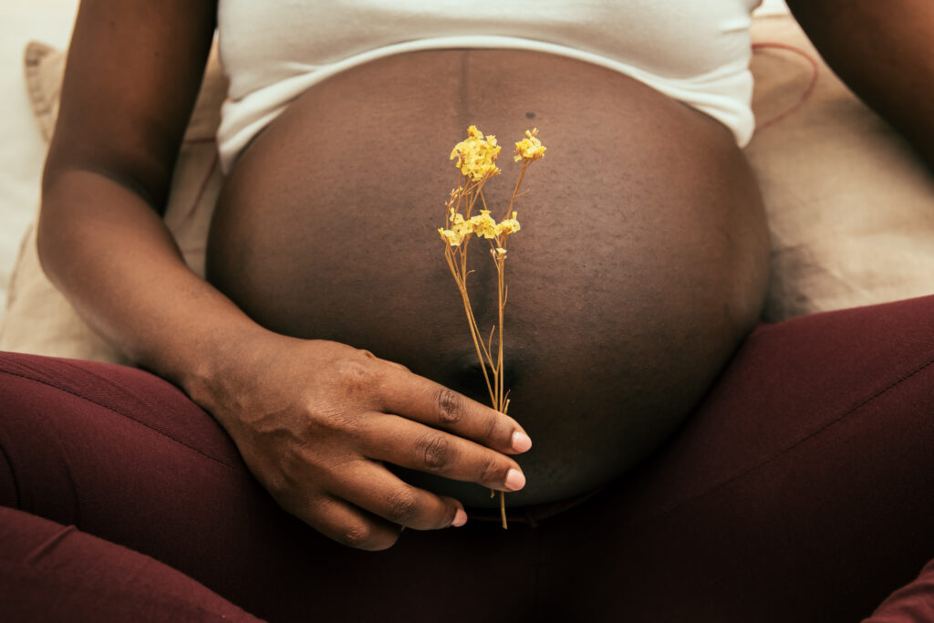 Pregnant women stages of labor holding a flower against pregnant belly.